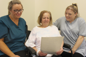 Speech and Language Therapist Assistants Kerry Mercer and Danielle Armstrong guide patient Shirley Ann Shurety in the weekly Shared Readers Group at Warrington Hospital's Stroke Unit.